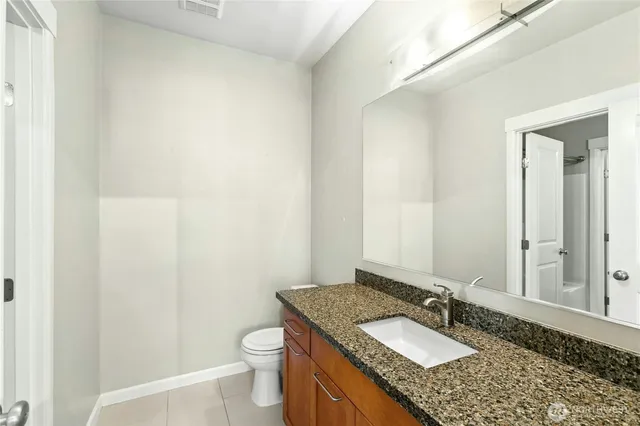 a bathroom with a granite countertop sink a toilet and a mirror