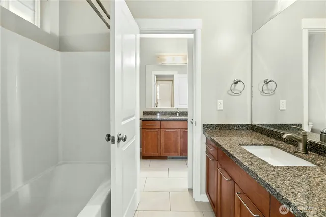 a bathroom with a granite countertop sink a mirror and a bathtub