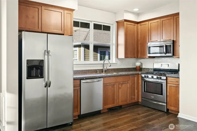 a kitchen with stainless steel appliances granite countertop a refrigerator and a stove top oven