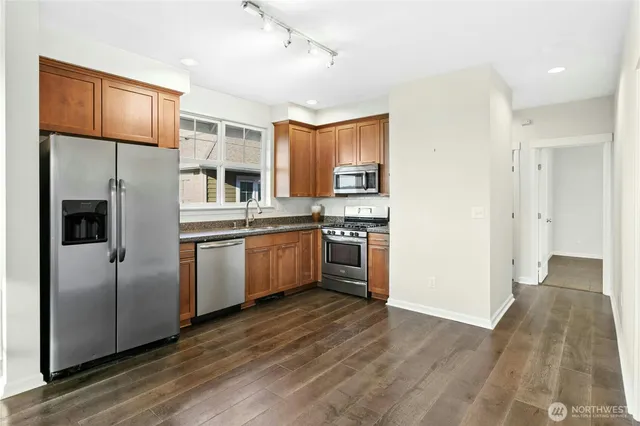 a kitchen with stainless steel appliances granite countertop a refrigerator a sink dishwasher a stove with wooden floor and cabinets