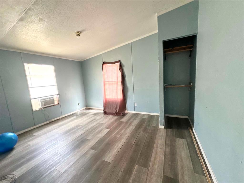 1275 John Wayne Road Kaufman, TX 75142 - Photo 10 of 11 Room featuring wood-finish flooring, light blue paneled walls, and white trim