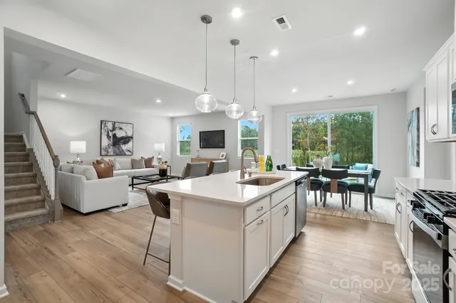 a large kitchen with stainless steel appliances a large center island attached withe living room