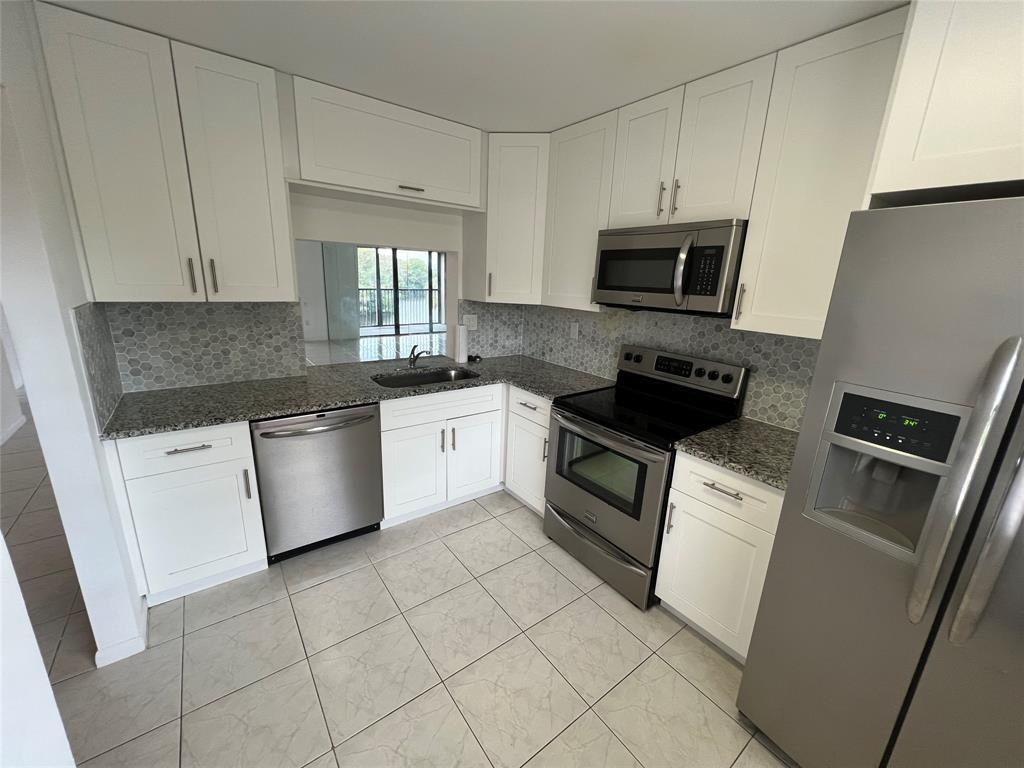 9273 Southwest 8th Street, Unit 109 Boca Raton, FL 33428 - Photo 20 of 22 a kitchen with a sink white cabinets and stainless steel appliances