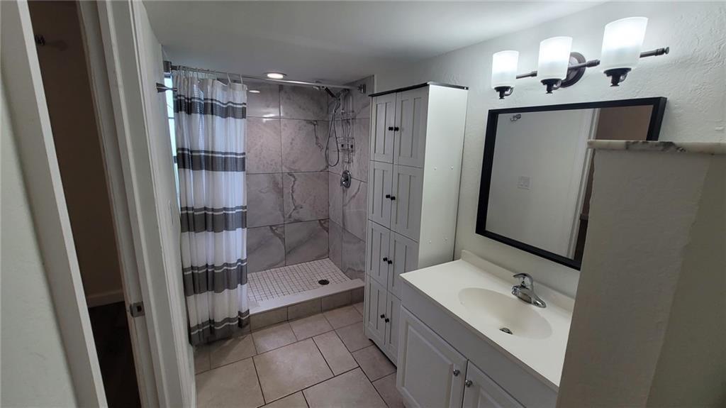 9273 Southwest 8th Street, Unit 109 Boca Raton, FL 33428 - Photo 7 of 22 a bathroom with a shower sink and mirror