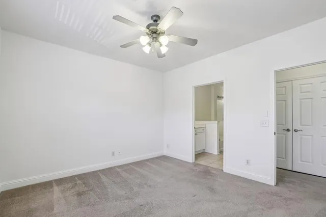a view of an empty room with chandelier fan