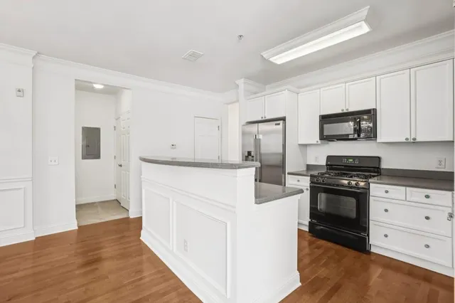 a kitchen with granite countertop white cabinets and stainless steel appliances