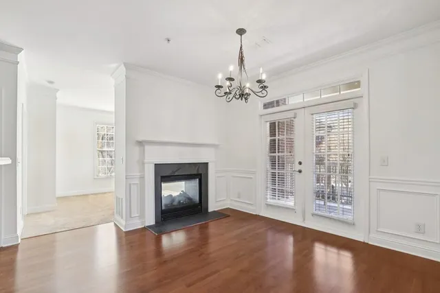 a view of an empty room with wooden floor fireplace and a window