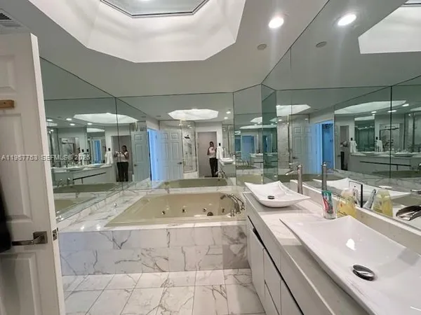 a bathroom with a tub a sink and mirrors