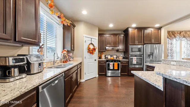a kitchen with stainless steel appliances granite countertop sink stove top oven and refrigerator