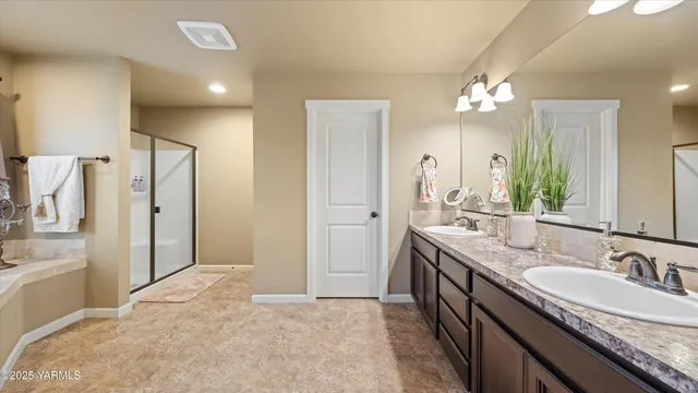 a spacious bathroom with a granite countertop sink a mirror a vanity and shower