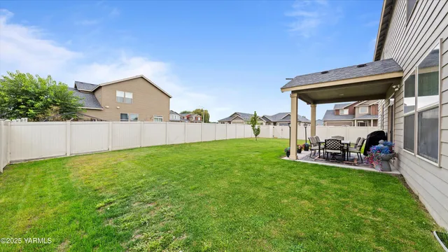 a view of a backyard with table and chairs a barbeque and wooden fence