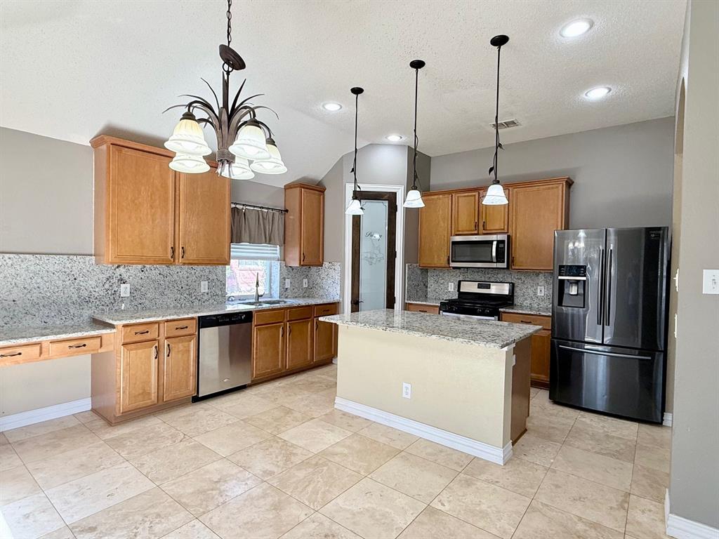 2607 Ridgeoak Trail Mansfield, TX 76063 - Photo 13 of 32 a kitchen with stainless steel appliances granite countertop a refrigerator a sink a oven and a wooden floor