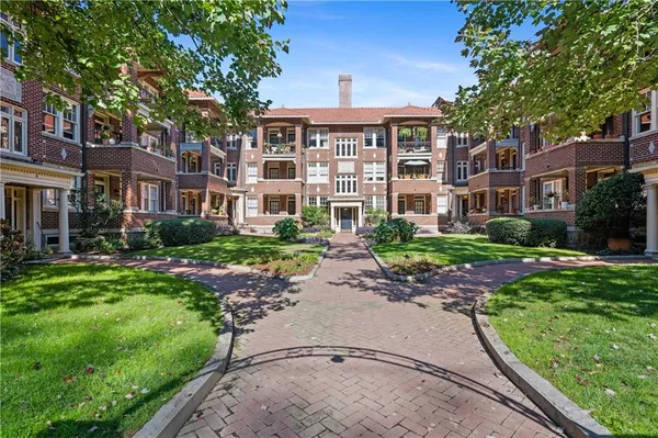 a front view of a building with garden and trees