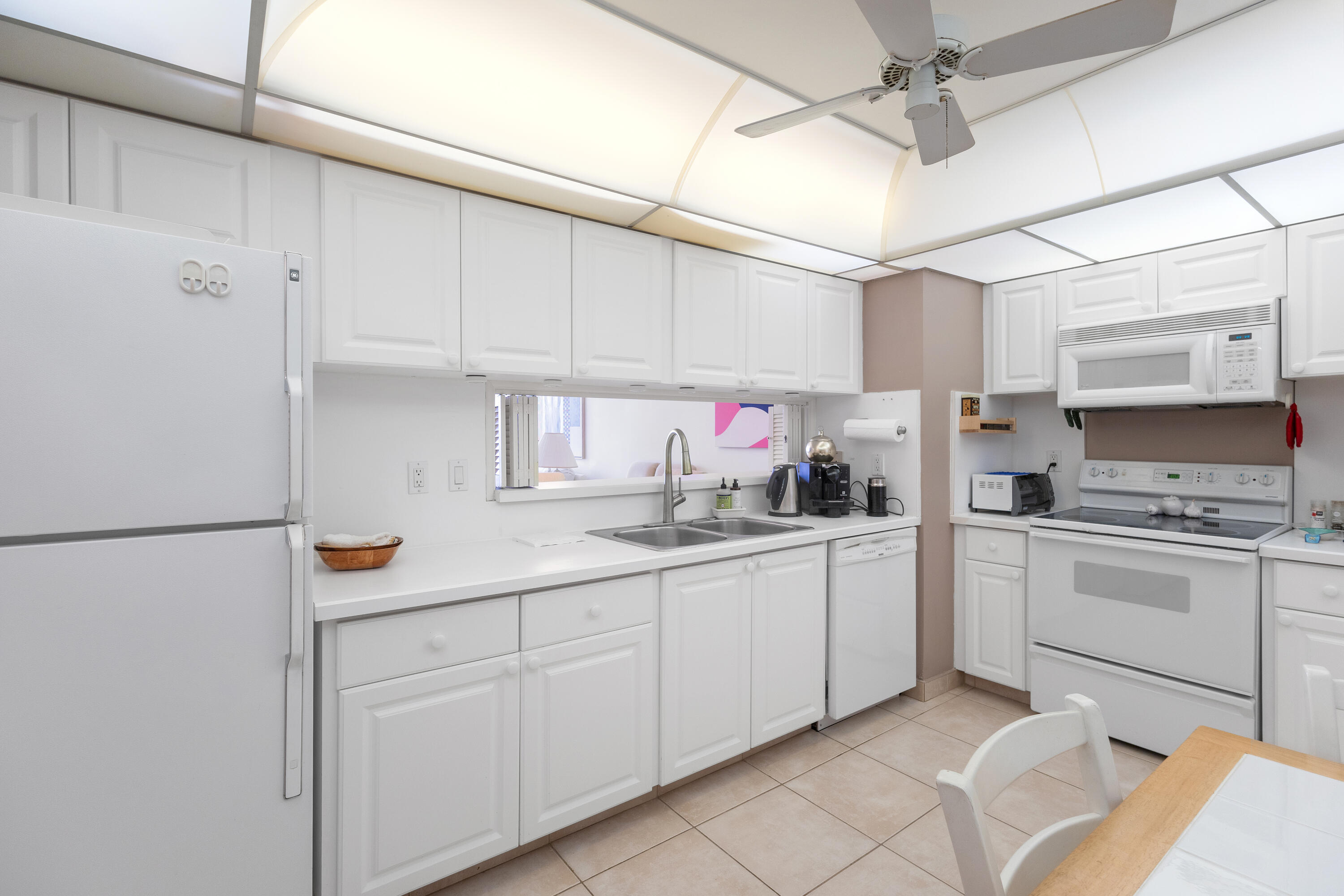 4750 South Ocean Boulevard, Unit 409 Highland Beach, FL 33487 - Photo 4 of 26 a kitchen with white cabinets and white appliances