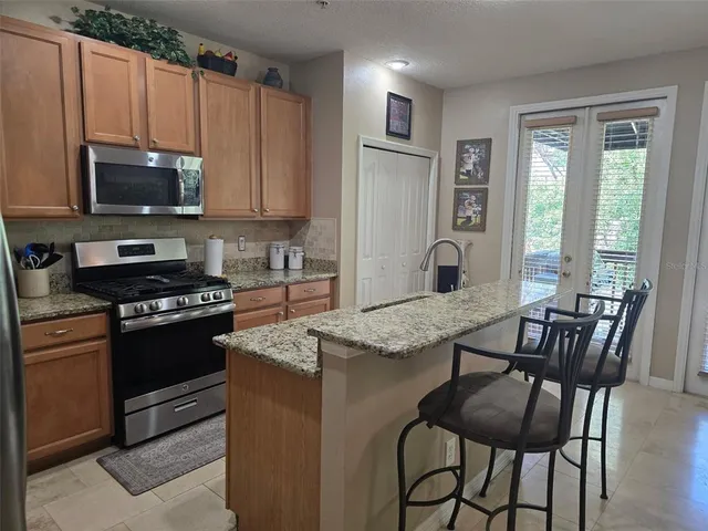 a kitchen with stainless steel appliances granite countertop a stove a sink dishwasher a microwave oven and a refrigerator with wooden floor