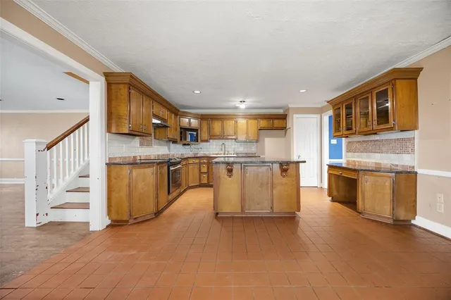 a kitchen with stainless steel appliances granite countertop a stove top oven a sink dishwasher and white cabinets with wooden floor