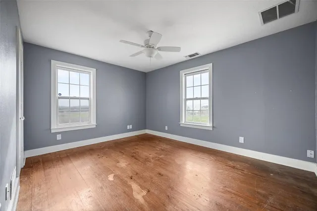 a view of an empty room with chandelier fan and a window