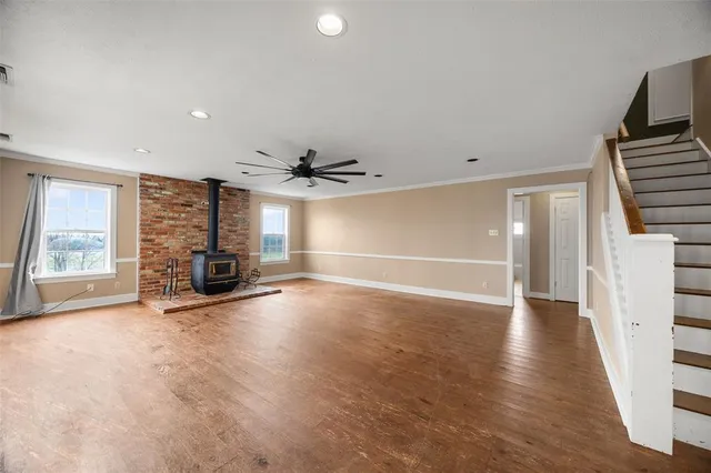 an empty room with wooden floor fireplace and windows