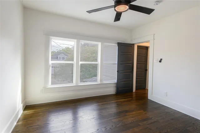 an empty room with wooden floor cabinet and windows