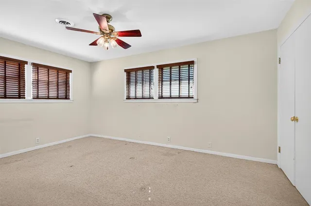 a view of a livingroom with a ceiling fan & windows