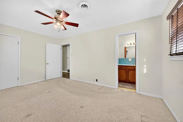 an empty room with chandelier fan and windows