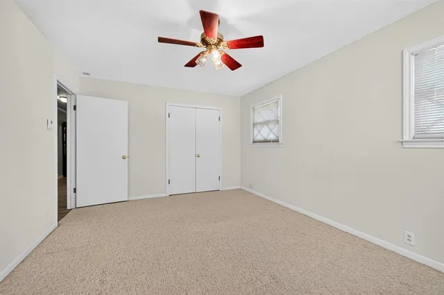 an empty room with ceiling fan and window