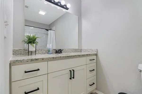 a bathroom with a granite countertop sink and a mirror