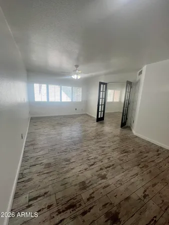 a view of empty room with wooden floor and fan