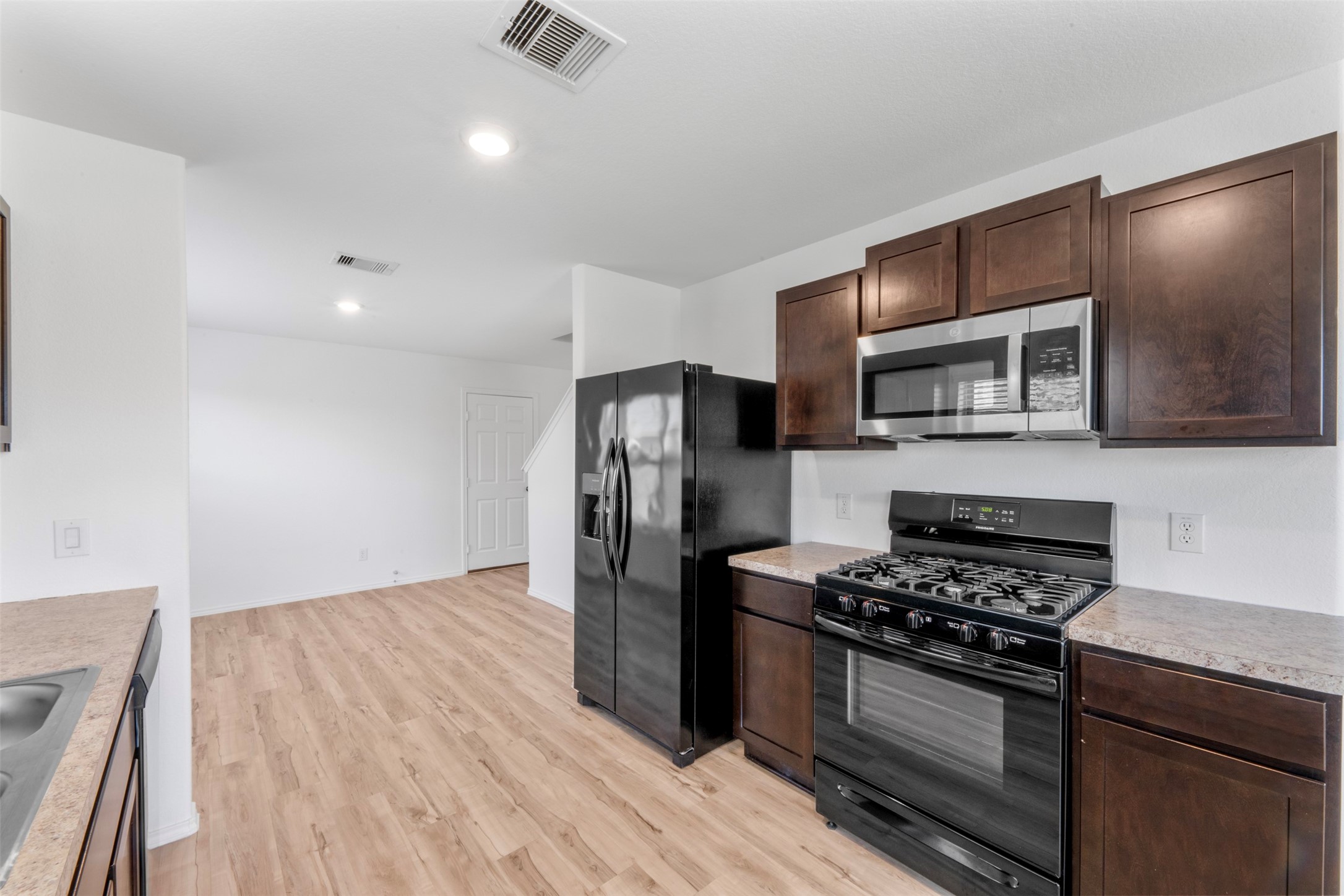 14602 Broadbury Pond Road Rosharon, TX 77583 - Photo 13 of 22 a kitchen with stainless steel appliances a stove a microwave and a hard wood floor
