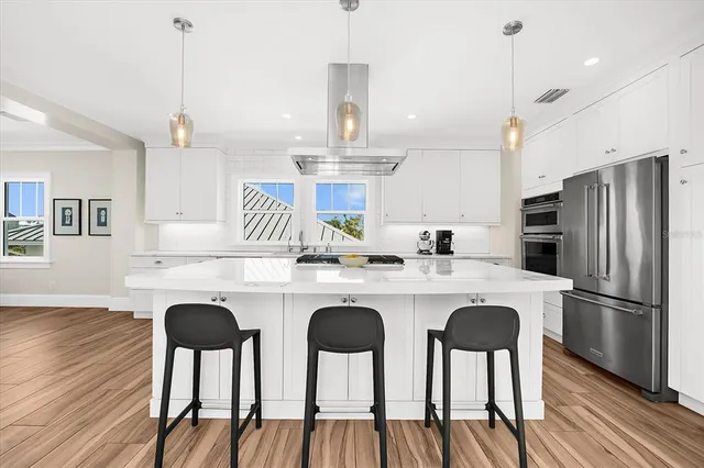 a kitchen with stainless steel appliances granite countertop a dining table chairs refrigerator and cabinets