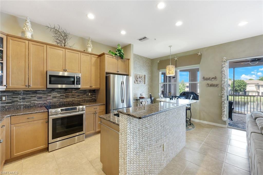 3530 Lansing Loop, Unit 202 Estero, FL 33928 - Photo 2 of 35 a kitchen with kitchen island granite countertop a stove a sink and a refrigerator