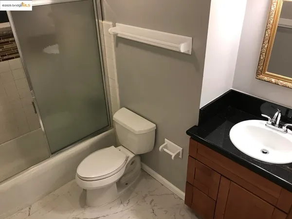 a bathroom with a granite countertop toilet and a sink