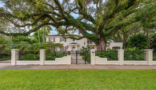 a front view of a house with a garden and tree