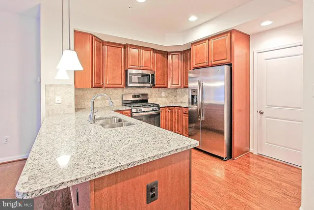 a kitchen with stainless steel appliances granite countertop a refrigerator a stove top oven a sink and dishwasher