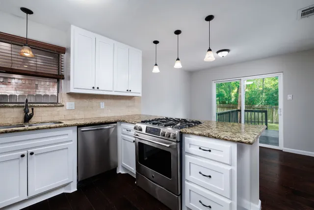 a kitchen with stainless steel appliances granite countertop a stove a sink and a microwave
