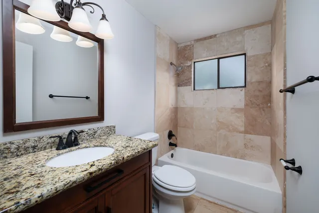 a bathroom with a granite countertop sink toilet and shower