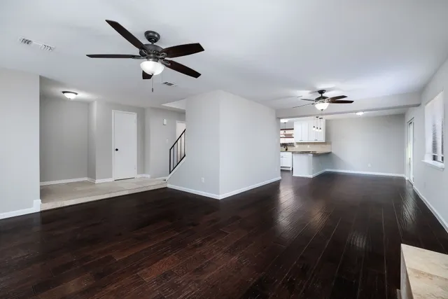 a view of empty room with wooden floor and ceiling fan