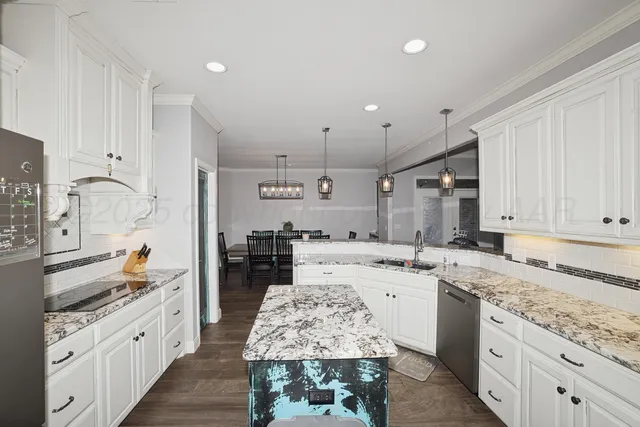 a large kitchen with kitchen island a sink stove and white cabinets