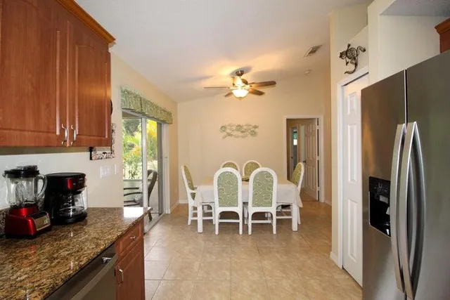 a dining room with stainless steel appliances granite countertop a refrigerator a stove a sink with island chairs and wooden floor