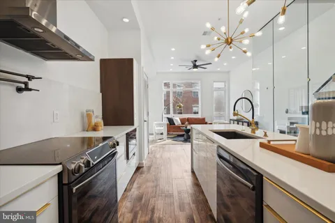 a kitchen with stainless steel appliances a stove a sink a refrigerator and chairs