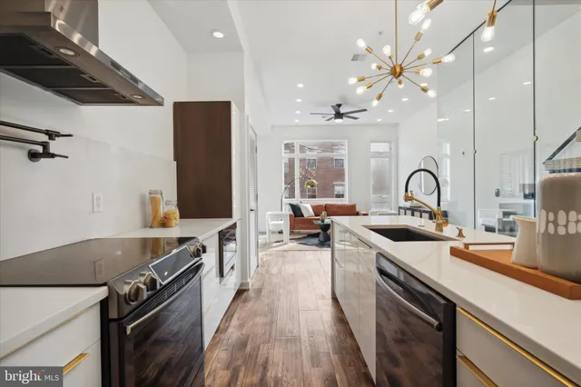a kitchen with stainless steel appliances a stove a sink a refrigerator and chairs