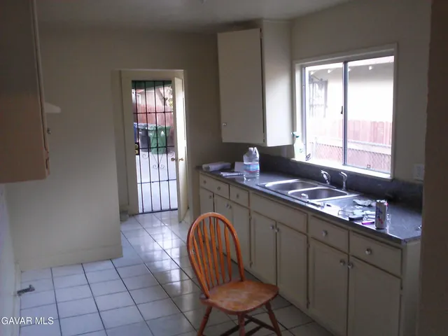 a kitchen with granite countertop a sink a stove cabinets and a window