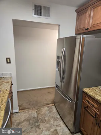 a view of a refrigerator in kitchen and an empty room