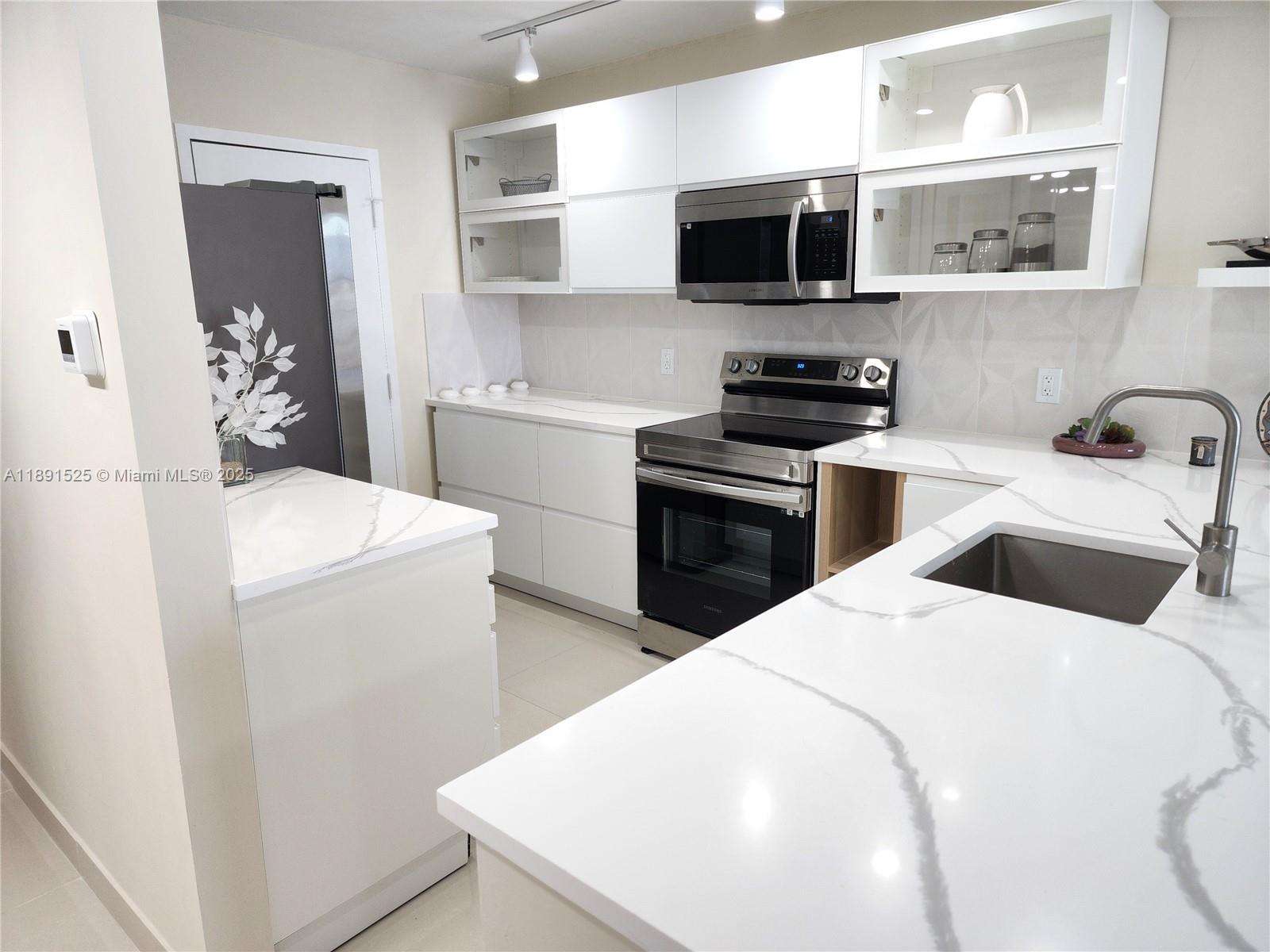 800 Southeast 20th Avenue, Unit 1109 Deerfield Beach, FL 33441 - Photo 5 of 19 a kitchen with a sink a stove and microwave