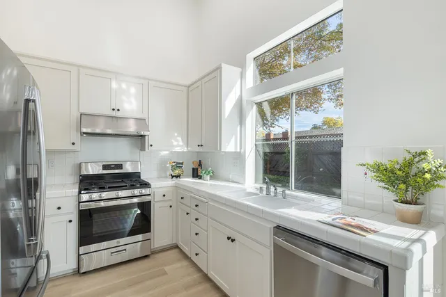 a kitchen with stainless steel appliances white cabinets and a stove top oven
