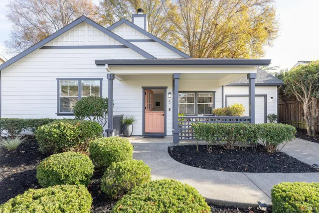 a front view of a house with a yard and potted plants