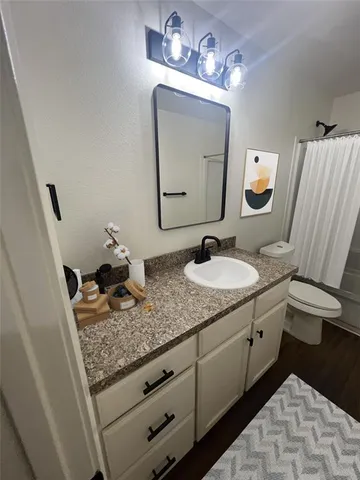 a bathroom with a granite countertop sink vanity mirror and toilet