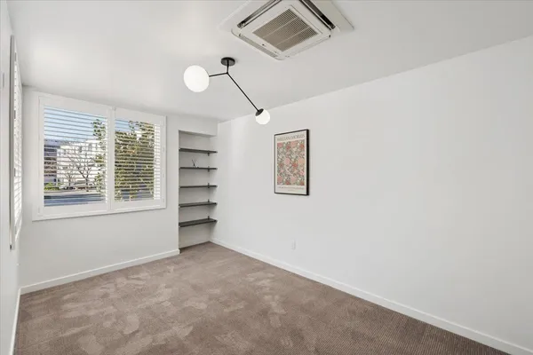 a view of an empty room with a window and cabinet