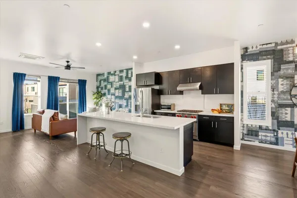 a kitchen with stainless steel appliances a stove top oven a sink a refrigerator white cabinets and wooden floor