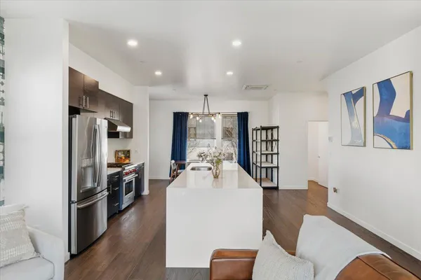 a room with stainless steel appliances furniture refrigerator and wooden floor